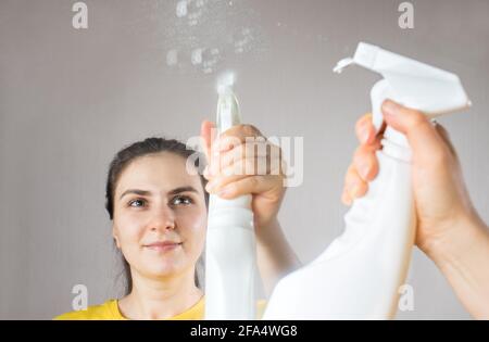 La femme de ménage nettoie le miroir avec un distributeur d'eau et un nettoyant pour vitres. Nettoyage de la maison. Service de nettoyage Banque D'Images