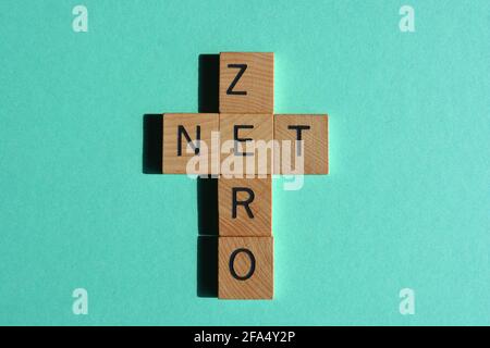 Net Zero, mots en lettres de l'alphabet en bois en forme de mots croisés isolés sur fond turquoise Banque D'Images