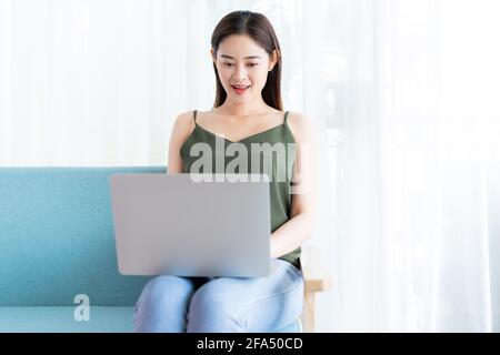 Femme asiatique assise avec un ordinateur portable sur un canapé Banque D'Images