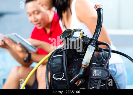 Asiatiques, divingmaster et étudiant à l'diver en vacances avec wetsuit et tablet computer Banque D'Images