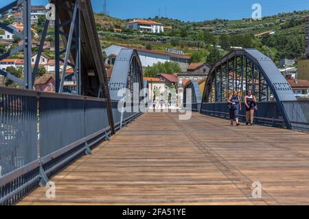 Regua / Portugal - 10/02/2020 : vue sur le pont métallique au-dessus du fleuve Douro sur le centre-ville de Peso da Regua, avec les touristes se promenant Banque D'Images