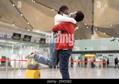 Réunion de couple africain sous Covid-19 nouvelle normalité. Homme et femme joyeux dans les masques hug à l'aéroport Banque D'Images