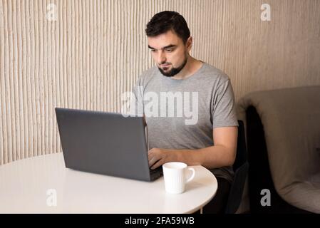 Jeune homme professionnel utilisant un ordinateur assis à la maison bureau. Travailleur indépendant à la maison Banque D'Images