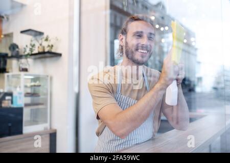 Homme debout derrière le verre dans la surface d'essuyage de café Banque D'Images