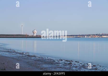Une longue exposition brouillant la marée haute sur la plage de Crosby montrant le phare au coin de Seaforth Dock. Dans la distance sur l'arête du Wirral Banque D'Images