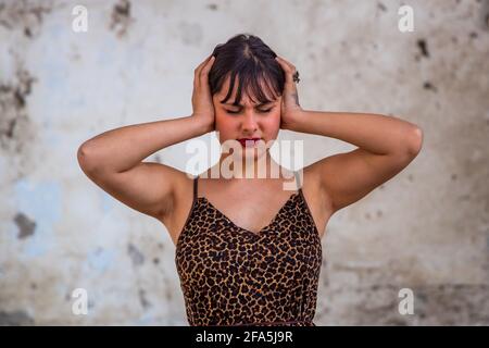 Portrait de la jeune femme brune stressée et inquiète, souffrant d'une migraine, les mains sur la tête regardant vers le bas. Copier l'espace, personnes. Banque D'Images