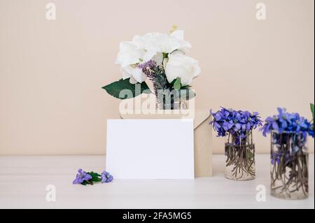 Carte, enveloppe et petites fleurs hepatica dans une bouteille en verre sur une table en bois. Violet Hepatica nobilis, Hepatica commun ou Anemone hepatica. Début de la spri Banque D'Images