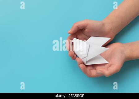 Les mains des enfants tiennent du papier blanc sur fond bleu Banque D'Images