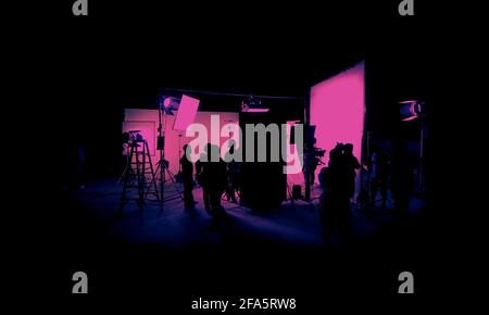 Images silhouettes de la production cinématographique. Dans les coulisses ou la bande-b de faire des films vidéo commerciaux. L'équipe de tournage lightman et le caméraman travaillent ensemble Banque D'Images