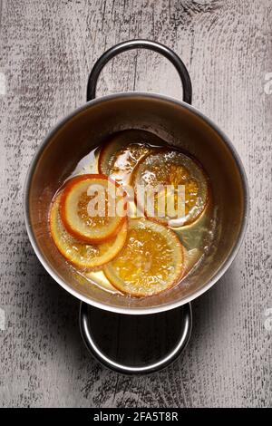 Tranches d'orange caramélisées dans une casserole sur fond de bois. Directement au-dessus. Banque D'Images