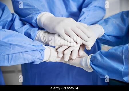 Gros plan des travailleurs médicaux se joignant entre eux comme symbole de l'unité. Groupe de médecins avec pile de mains portant des gants stériles blancs. Concept d'unité, travail d'équipe et médecine. Banque D'Images