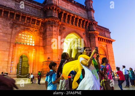 Mumbai, Maharashtra, Inde : les gens posent pour les selfies au crépuscule devant la porte illuminée de l'Inde arche monumentale construite entre 1913 et 1924 i Banque D'Images