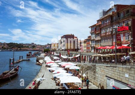 Porto, Portugal - 27 juillet 2018 : Maisons de ville au bord du Douro dans le quartier de Ribeira, classé au patrimoine mondial de l'UNESCO. Personnes fortuites en arrière-plan. Banque D'Images