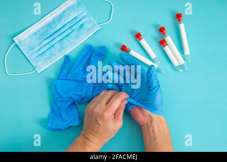 mains retirer le gant sur fond bleu. Le concept de traitement, la protection contre les virus, la grippe, le rétablissement, arrêter le coronavirus. Banque D'Images