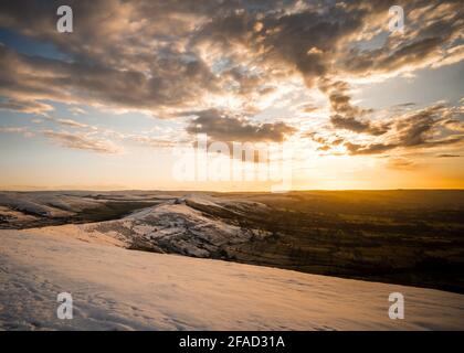 MAM Tor Derbyshire Peak District crêtes randonnée en hiver la vallée de la neige et le soleil d'orange doré s'élevant sur une atmosphère de moody hiver montagne enneigée Banque D'Images