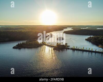 Route étroite traversant le lac Saimaa dans la région de Pistohiekka à Puumala, en Finlande. Magnifique coucher de soleil se reflétant sur l'eau. Banque D'Images