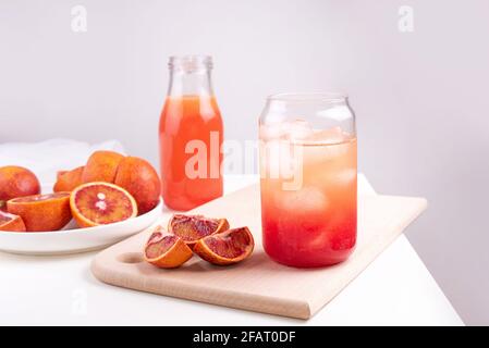 Eau de fruit dans un verre avec des glaçons, limonade orange rouge, boisson rafraîchissante d'été sur fond blanc, gros plan. Banque D'Images