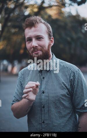 Smiley hipster style homme fumée cigarette à l'extérieur Banque D'Images