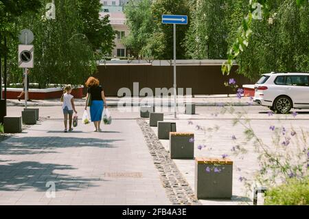 Maman et fille portent leurs achats dans la rue piétonne de la ville verte Banque D'Images