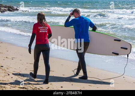 Surfeurs à Branksome Dene Chine, Poole, Dorset Royaume-Uni lors d'une chaude journée ensoleillée en avril Banque D'Images