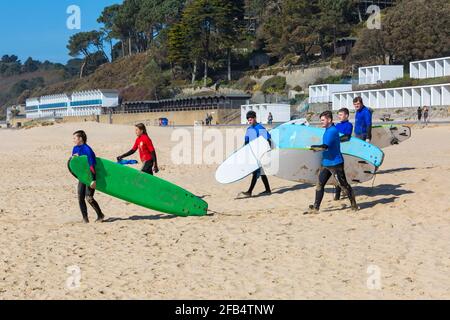 Surfeurs à Branksome Dene Chine, Poole, Dorset Royaume-Uni lors d'une chaude journée ensoleillée en avril Banque D'Images
