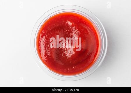 Petite tasse de sauce tomate, vue de dessus sur fond blanc Banque D'Images