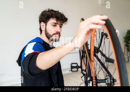Jeune homme examinant un pneu de vélo d'upturnt à la maison Banque D'Images