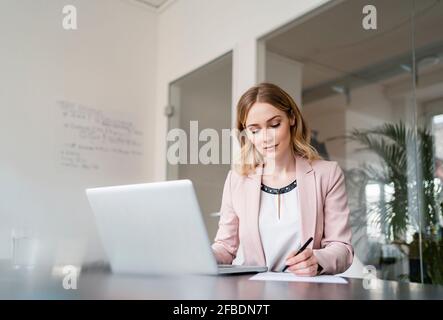 Femme professionnelle écrivant sur le document à la table de conférence au bureau Banque D'Images