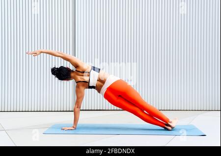 Femme sportswoman faisant le côté de la planche pose devant le mur Banque D'Images