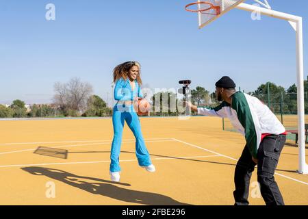 Bon vlogging masculin et féminin avec basketball sur le terrain de sport Banque D'Images