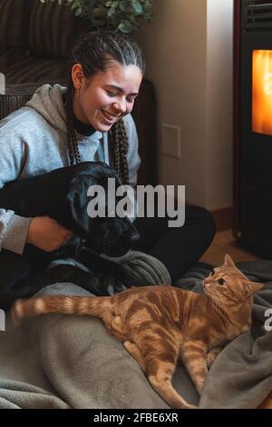 Femme adolescente souriante assise avec des animaux de compagnie à la maison Banque D'Images