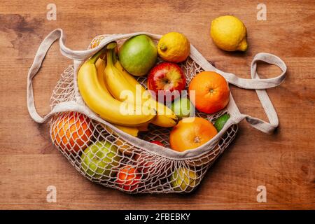 Sac en maille de coton réutilisable avec fruits frais posés sur du bois tableau Banque D'Images