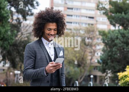 Beau jeune homme d'affaires travaillant sur le téléphone portable dans la ville Banque D'Images