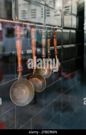 Plusieurs ustensiles de cuisine suspendus sur un mur vu à travers le verre dans le restaurant Banque D'Images