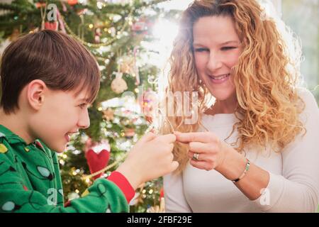 Bonne mère et fils tenant le triangle avec arbre de Noël arrière-plan Banque D'Images
