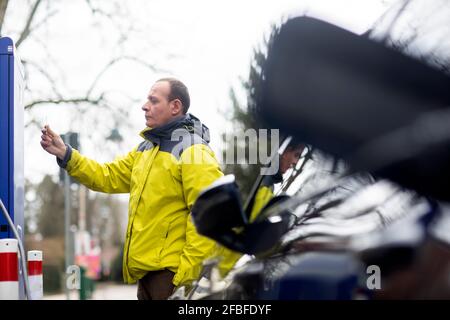 Homme mature utilisant la carte de crédit à la station de charge de voiture électrique Banque D'Images