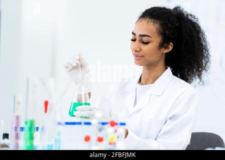 Une chercheuse pipetant du liquide dans un flacon lorsqu'elle travaille en laboratoire Banque D'Images