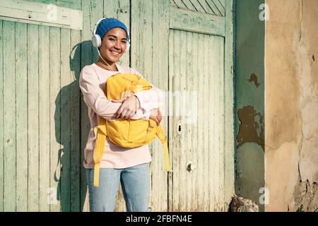 Femme souriante avec casque portant sac à dos devant du bois porte Banque D'Images
