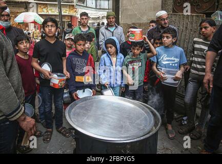 Gaza, Palestine. 23 avril 2021. Les Palestiniens reçoivent gratuitement de la nourriture distribuée par Walid Al-Hattab (non représenté) aux familles pauvres pendant le mois Saint du Ramadan dans le quartier de Shejaiya à Gaza. Crédit : SOPA Images Limited/Alamy Live News Banque D'Images