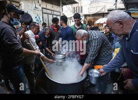 Gaza, Palestine. 23 avril 2021. Le palestinien Walid Al-Hattab (portant une chemise à carreaux) distribue gratuitement de la nourriture aux familles pauvres pendant le mois Saint du Ramadan dans le quartier de Shejaiya à Gaza. Crédit : SOPA Images Limited/Alamy Live News Banque D'Images