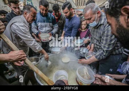 Gaza, Palestine. 23 avril 2021. Le palestinien Walid Al-Hattab (portant une chemise à carreaux) distribue gratuitement de la nourriture aux familles pauvres pendant le mois Saint du Ramadan dans le quartier de Shejaiya à Gaza. Crédit : SOPA Images Limited/Alamy Live News Banque D'Images