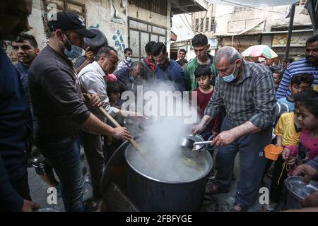 Gaza, Palestine. 23 avril 2021. Le palestinien Walid Al-Hattab (portant une chemise à carreaux) distribue gratuitement de la nourriture aux familles pauvres pendant le mois Saint du Ramadan dans le quartier de Shejaiya à Gaza. Crédit : SOPA Images Limited/Alamy Live News Banque D'Images