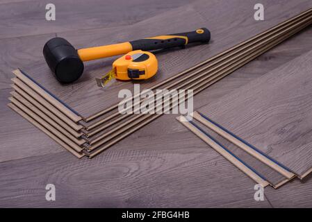 Marteau et mètre ruban sur les panneaux stratifiés, outils de menuisier pour poser le stratifié dans la pièce. Banque D'Images