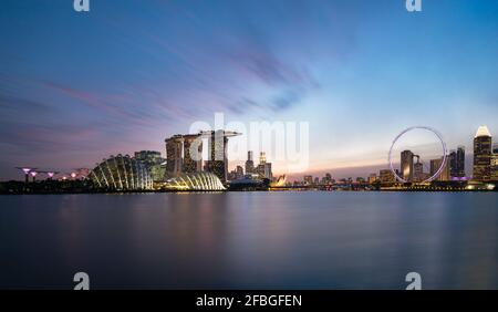 Singapour, longue exposition de Marina Bay au crépuscule avec l'hôtel Marina Bay Sands et Singapore Flyer en arrière-plan Banque D'Images