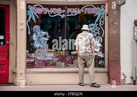 Manitou Springs Colorado USA 9-19-2018 Homme en chemise tropicale et le chapeau et les sandales sont peints et décorés fenêtre de boutique de boho fermée vendant des hanches Banque D'Images