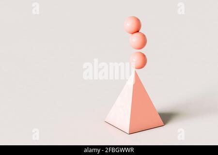 Pyramide abstraite rose avec trois sphères en équilibre sur le dessus arrière-plan de couleur crème Banque D'Images