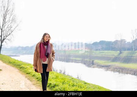 Femme souriante marchant sur la rive de la rivière Banque D'Images