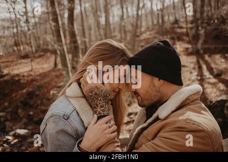 Hipster homme debout par une petite amie assis sur une rambarde en bois à la forêt pendant l'automne Banque D'Images