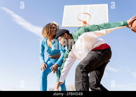 Joyeux homme et femme jouant au basket-ball sur le terrain Banque D'Images