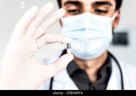 Un médecin portant un masque facial de protection tenant une capsule Banque D'Images